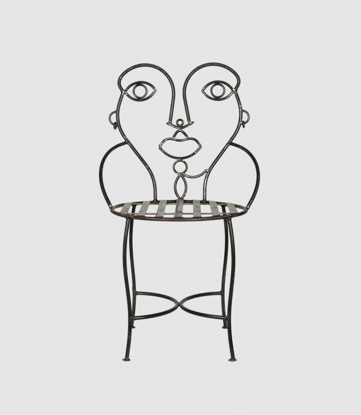 A metal chair with a backrest designed to resemble a stylized human face, featuring wire outlines for eyes, nose, and lips, and a slatted seat.