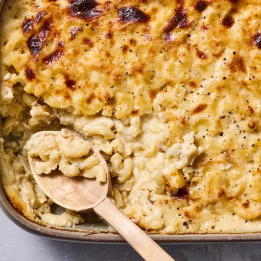 Baked macaroni and cheese in a rectangular dish with a wooden serving spoon.